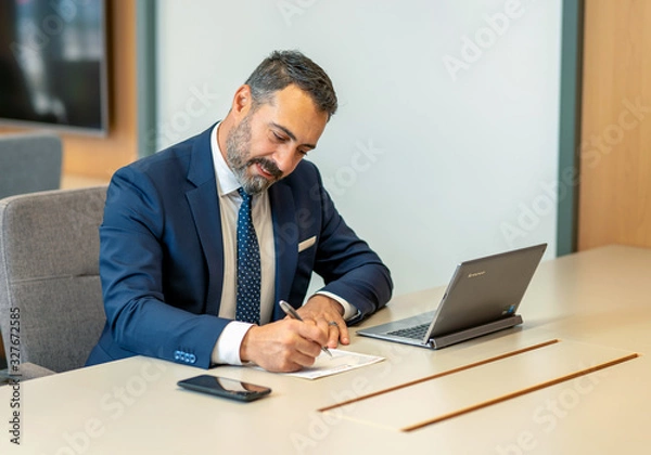 Obraz A male employee filling out contracts and forms at the office desk