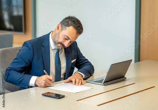 Obraz A male employee filling out contracts and forms at the office desk