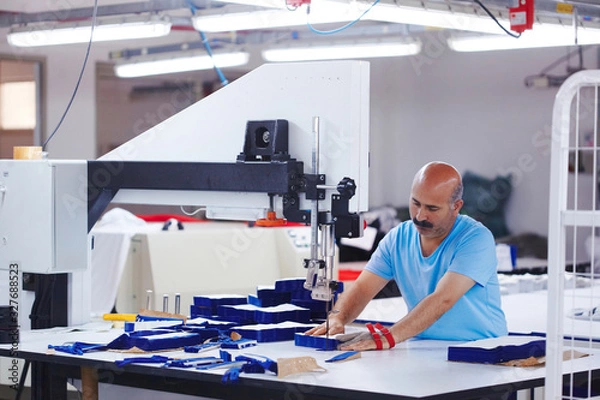 Fototapeta The cutter works on the machine at the clothing factory