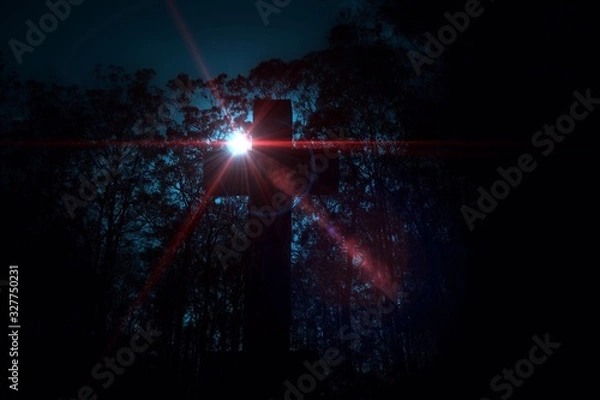 Fototapeta Cross in a cemetery with a rising sun scene
