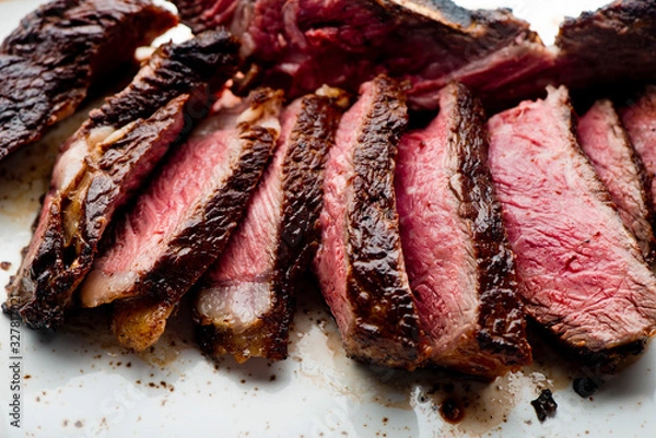 Fototapeta Steak. Grade A, grass fed angus beef. Traditional classic New York steakhouse menu favorite. T-bone steak, bone in, cooked to medium to rare and sliced. 