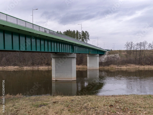 Fototapeta landscape with green bridge over slow flowing river