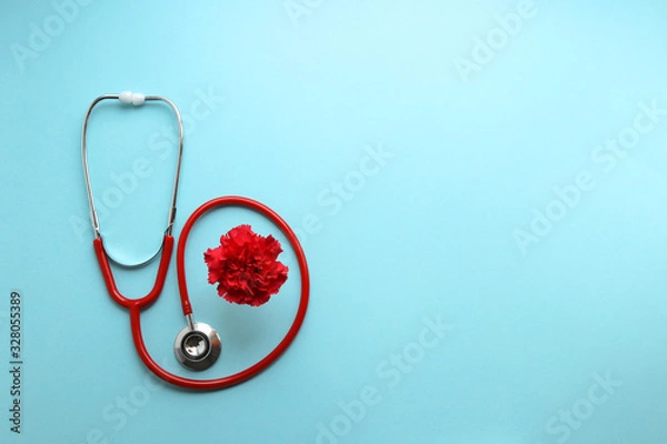 Fototapeta Still life red stethoscope and red carnation on a blue background symbolize the day of the doctor