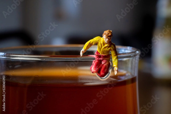 Obraz Miniature guy is trying to climb out of a glass