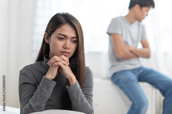 Fototapeta Lover couple relationship problems. Sad young wife sitting on the bed back to back from husband after argument.