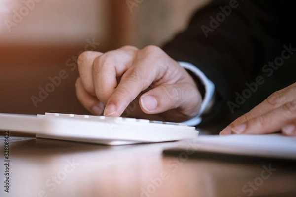 Fototapeta Businessman analyzing investment charts and pressing calculator buttons over documents. Accounting Concept.