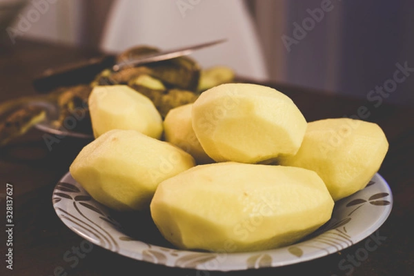 Fototapeta Peeling potatoes with a knife at home
