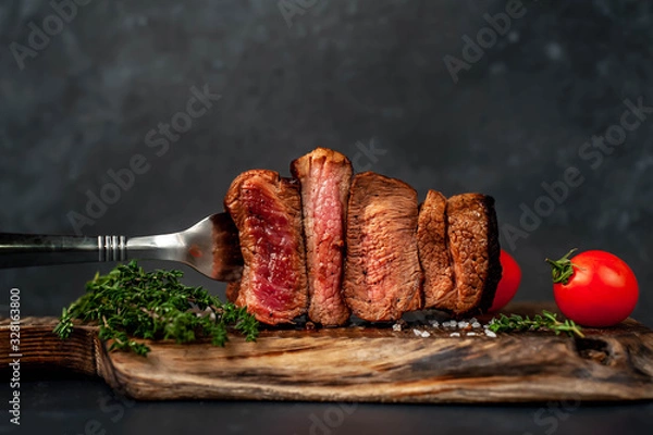 Fototapeta four steaks on  fork on a cutting board on a stone background.Four types of meat frying Rare, Medium, Medium Well, Well Done