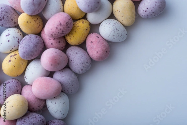 Fototapeta Colorful mini Easter eggs on a plain back ground with copy space