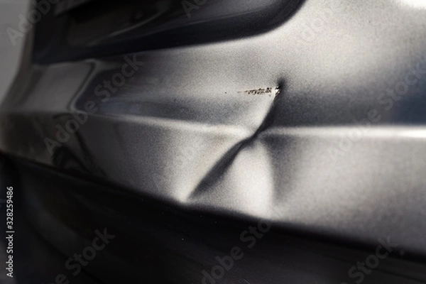 Fototapeta A dent in the body of a silver car in exciting light.