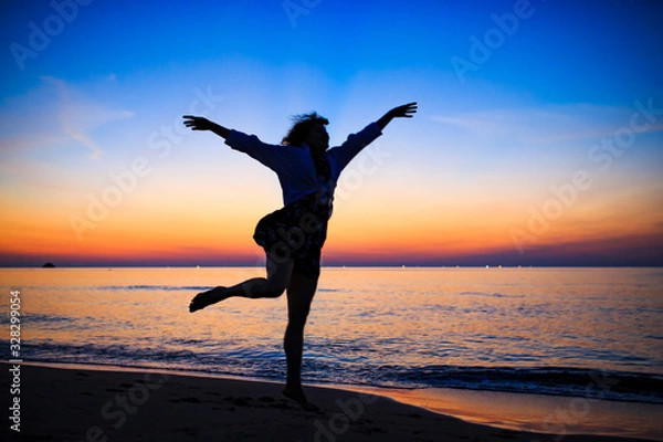 Fototapeta 夕暮れの海辺で踊る白人女性