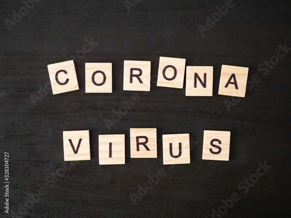 Fototapeta Coronavirus word made of wood block. Coronavirus text on dramatic atmosphere black wooden table. Coronavirus concept top view.