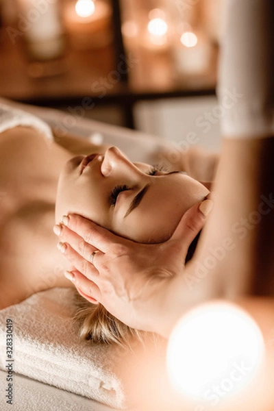 Obraz Hands of the masseuse make a manual massage of the head to a beautiful client woman. Concept of scalp treatment and hair growth stimulation
