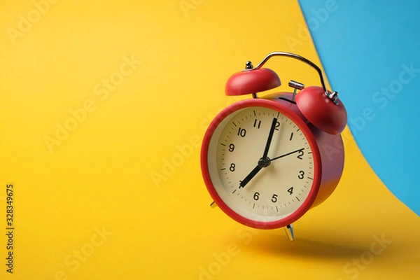 Fototapeta Red retro alarm clock floating in the air with yellow and blue background.