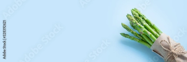 Fototapeta bunch of fresh green asparagus on a blue background, banner format