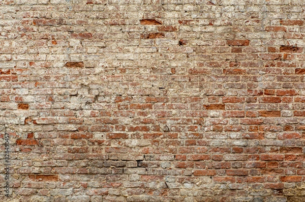 Fototapeta Old brick wall. Brickwork from an old brick in a rustic style. The structure and pattern of the destroyed stone wall. Copy space