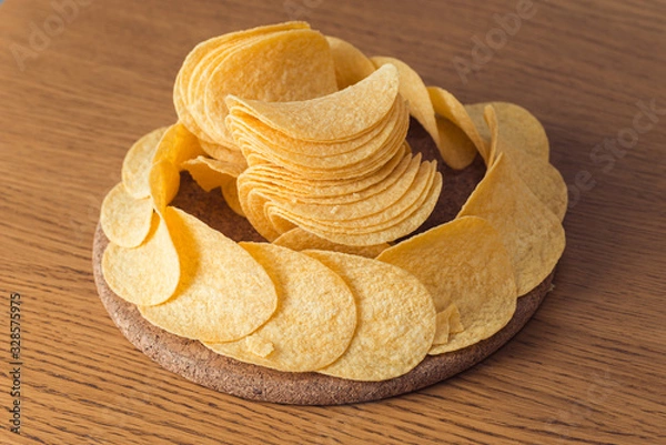 Obraz Delicious potato chips, laying on wooden table background