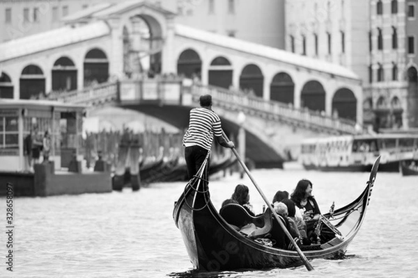 Fototapeta Iconic black and white view of a gondolier rowing on the Grand Canal, with the Rialto bridge and a water-bus in the distance