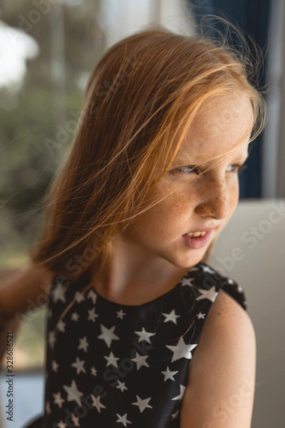 Obraz Little girl with red hair shows different emotions. Sadness, joy and happiness. She smiles and cries. In a black dress with skin pigment on her face, freckles