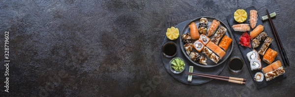 Fototapeta sushi rolls with rice and fish, soy sauce on a dark stone background