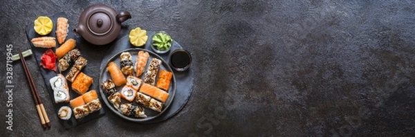 Fototapeta sushi rolls with rice and fish, soy sauce on a dark stone background