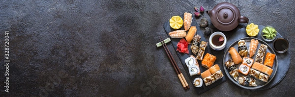 Fototapeta sushi rolls with rice and fish, soy sauce on a dark stone background