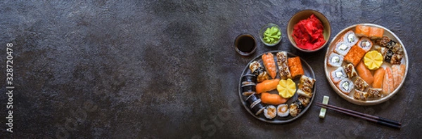 Fototapeta sushi rolls with rice and fish, soy sauce on a dark stone background