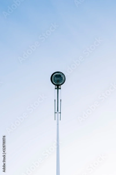 Obraz A modern city street lamp in the center of the photograph with the blue sky clear in the background