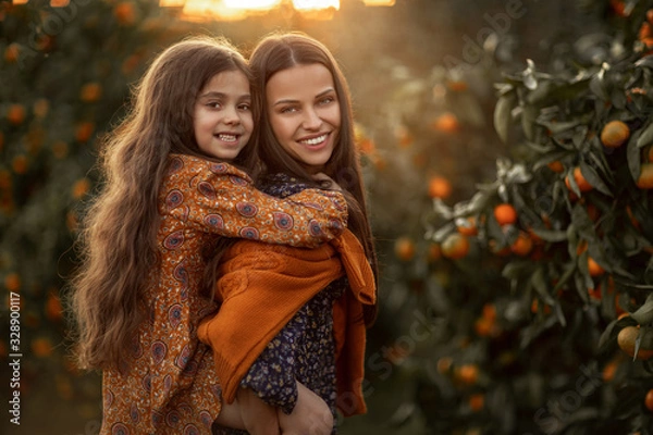 Obraz Mom and daughter have fun together and play in the garden with Agriculture trees.