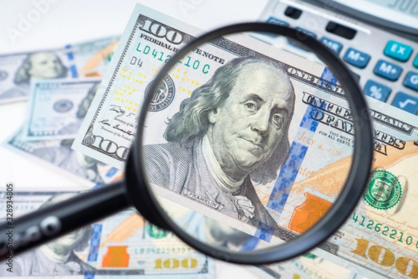 Fototapeta Money under the magnifying glass. Concept - financial market analysis. The protective line on the money. Defining fake bills. Concept - blue line as a sign of authenticity. Search for security signs