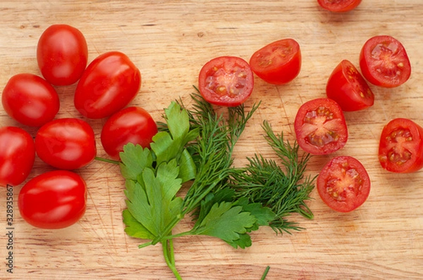 Fototapeta Ripe cherry tomatoes with parsley and dill in a wooden cutting board, top view
