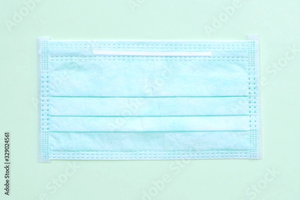 Fototapeta Protective face mask isolated on a green background.Procedure mask from bacteria corona virus. Protection concept.