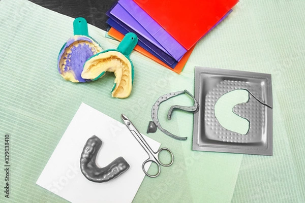 Fototapeta Process of creating custom mouthguard. Silver sports mouthguard with pieces of plastic material and tools.