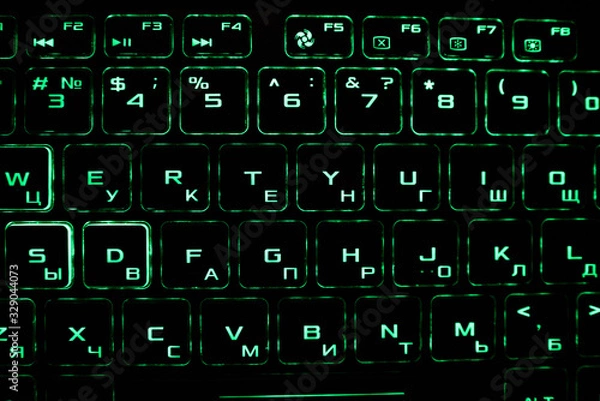 Fototapeta Computer keyboard with Russian and English layout. Backlit by neon light.