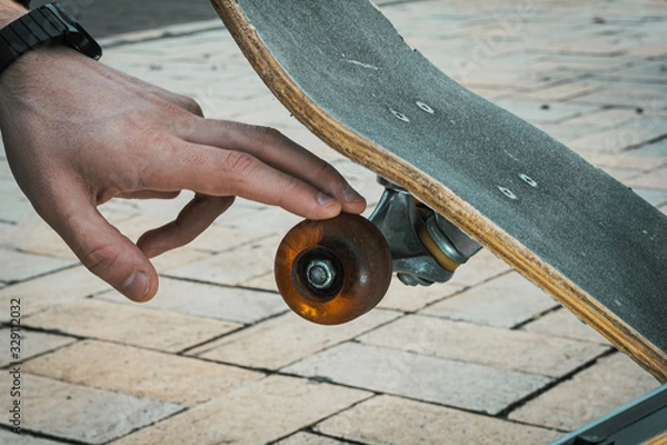 Fototapeta close up of hand touching skateboard wheel
