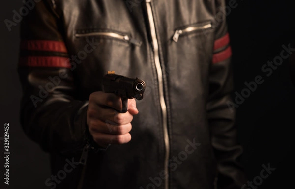 Fototapeta The hand presses the trigger of the gun and the flame from the shot escapes from its muzzle