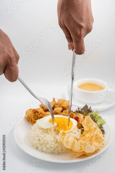 Obraz Buttermilk chicken rice with ingredients isolated on white with fried egg and salad. Fork and knife cut the fried egg.