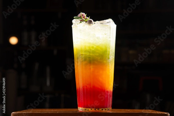 Obraz red orange yellow and green seperate layer color with soda in one glass decorate by mixed berry on top on wood table in blur coffee bar background stock photo
