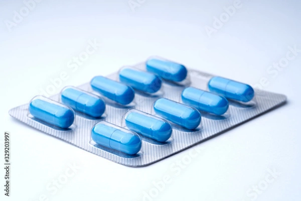 Fototapeta Closeup of blue pills in packaging on a white background with texture.