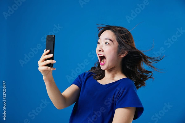 Fototapeta スマートフォンを持って驚く女性