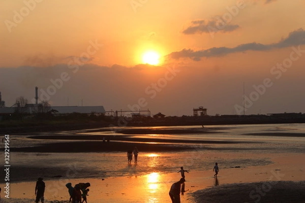 Fototapeta atmosphere beach sunset time many silhouettes of people playing on the shore