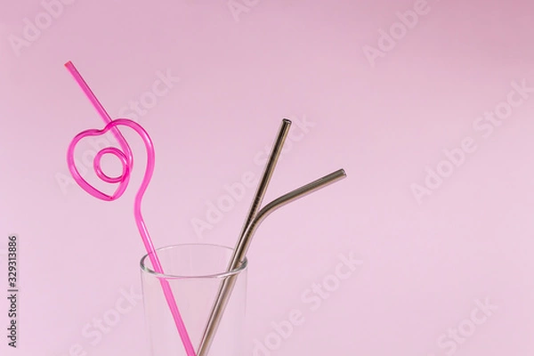 Obraz Reusable stainless steel cocktail tubes and plastic tube in a glass on a pink background. The concept of protecting the environment and avoiding the use of plastic. Zero waste. Side view, copy space.