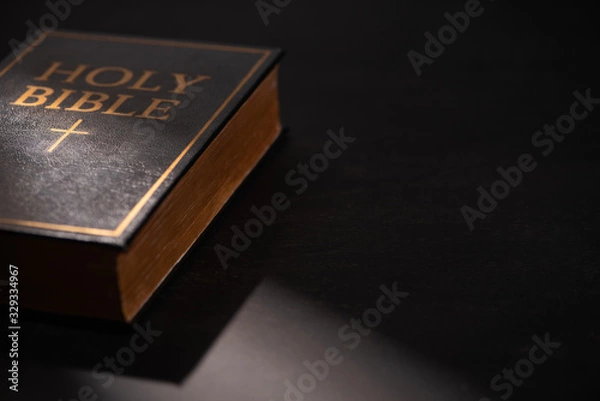 Fototapeta holy bible on black dark background with sunlight