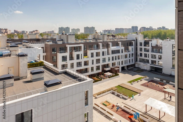 Fototapeta house building exterior with flat roof and playground for children mixed-use urban multi-family residential district area development sunny day