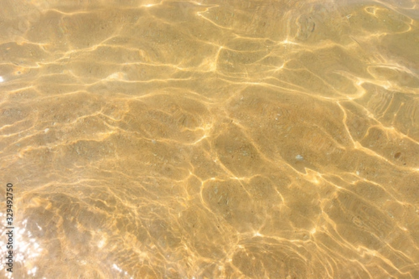Fototapeta Ripples of water waves reflecting texture on a sandy beach bottom