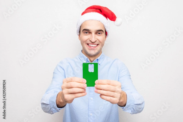 Fototapeta Man in Santa Claus hat shows that you need a SIM card, portrait, white background
