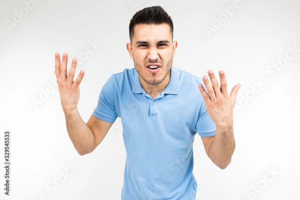 Fototapeta handsome guy in a blue t-shirt screaming at the camera on a white isolated background