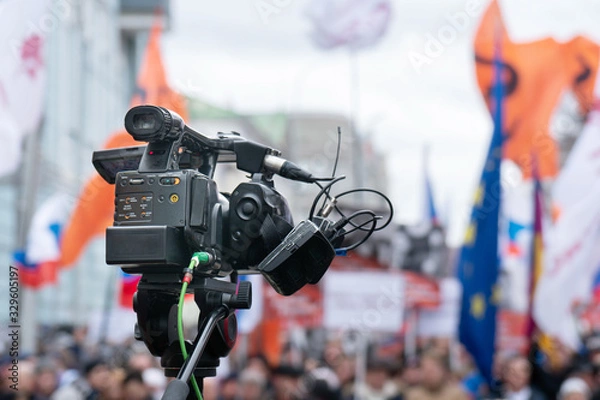 Fototapeta Videographer is reporting from a city street during a mass political action in Moscow, Russia. Camera is up of the crowd