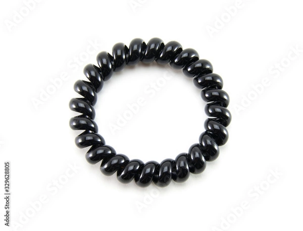 Fototapeta One black spiral elastic for hair on a white isolated background. A flexible plastic item for a female hairstyle or an arm bracelet. Elastic accessory