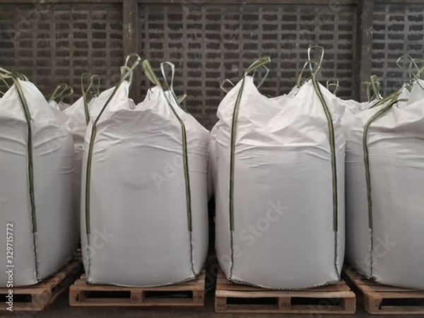Fototapeta White hemp sacks containing chemical fertilizer Large yellow-green sidebar placed on wooden pallets. To wait for delivery to customers
